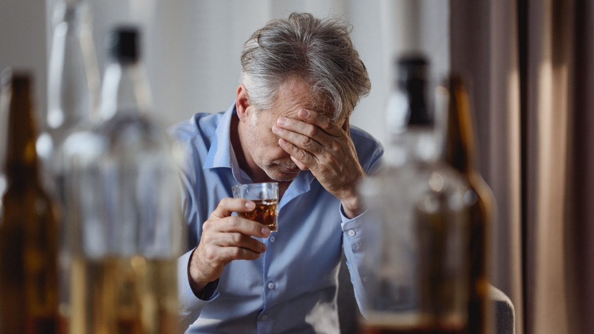 Alcoholic man with bottles on alcohol