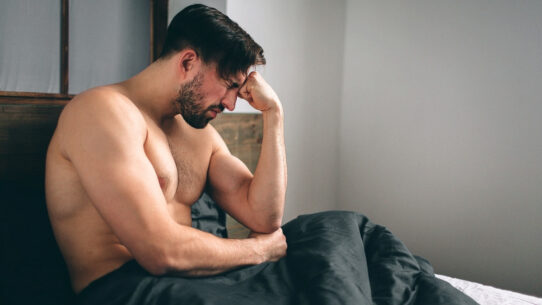 Sad man sitting on bed suffering from erectile dsyfunction