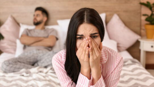 a couple sits on bed where woman suffers from Female sexual dysfunction