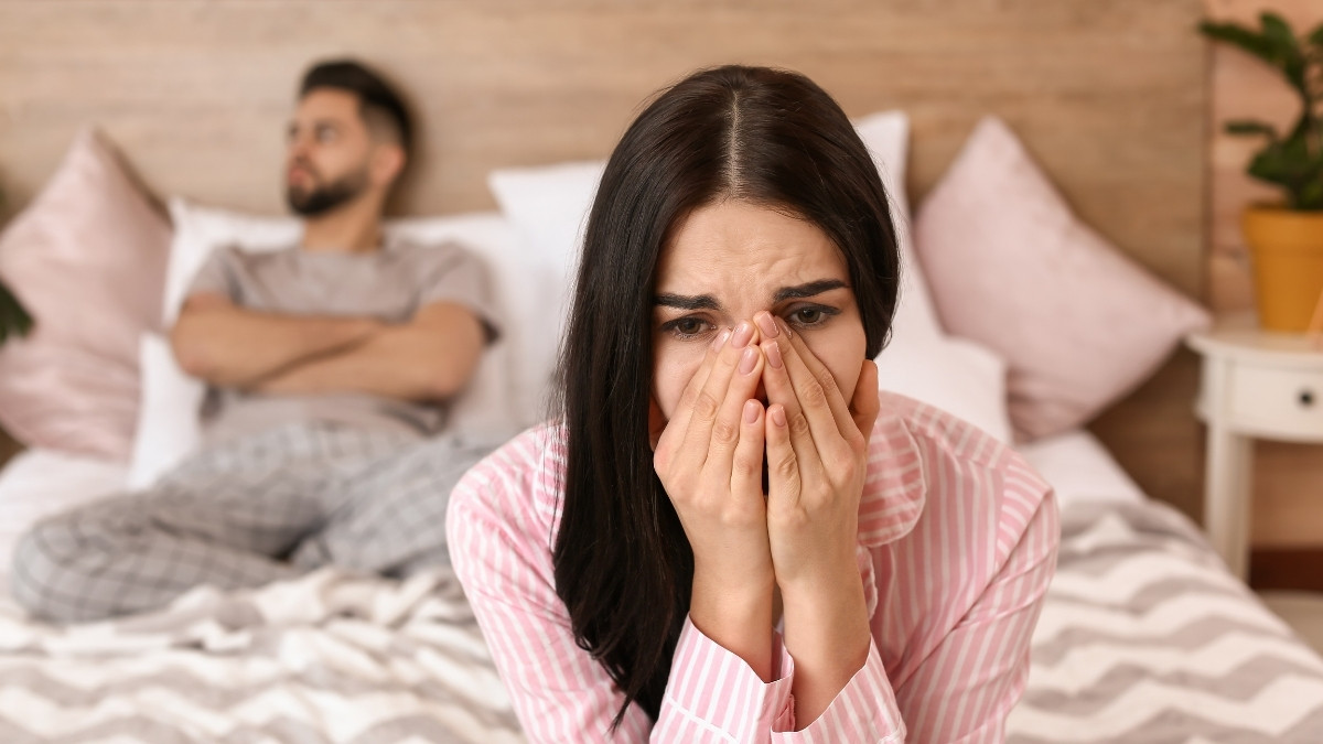 a couple sits on bed where woman suffers from Female sexual dysfunction