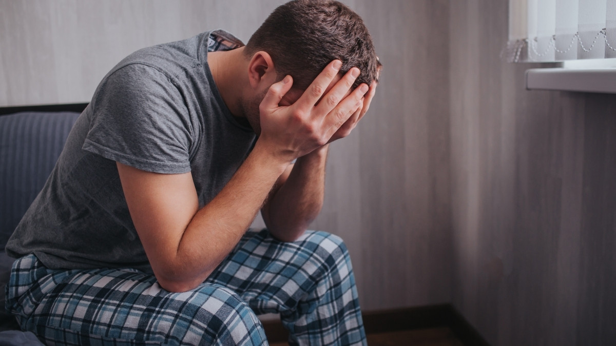 man sitting holding head in dismay